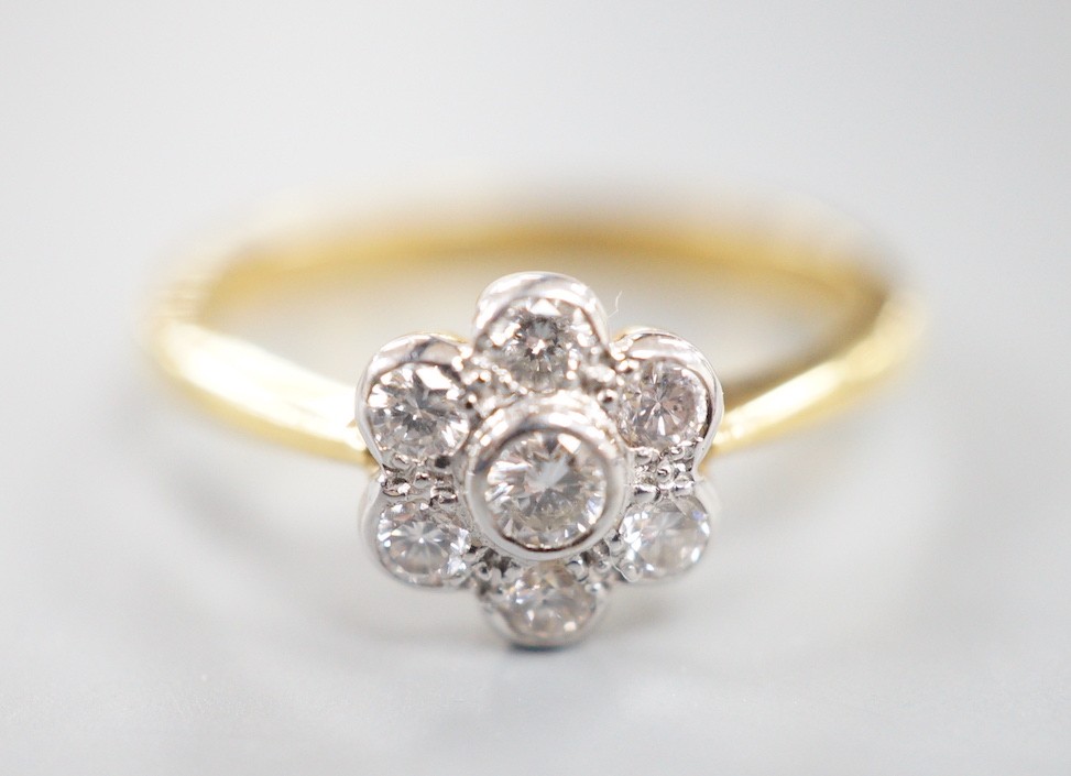 A modern 18ct gold and collet set seven stone diamond set flower head cluster ring, size O, gross weight 3.7 grams